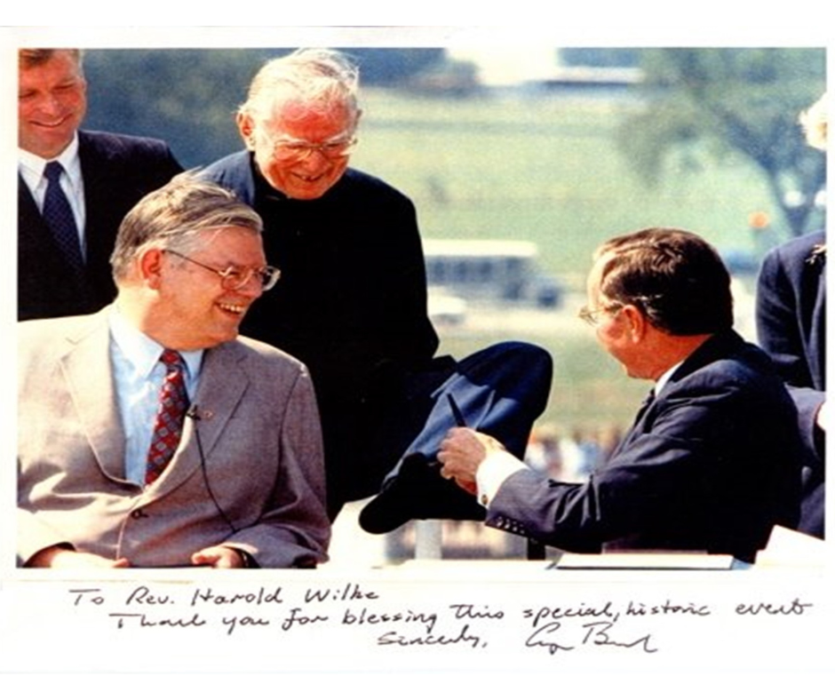 Rev. Harold Wilke at signing of the ADA Rev. Wilke using his toes to accept a pen from President Bush at the ADA signing.