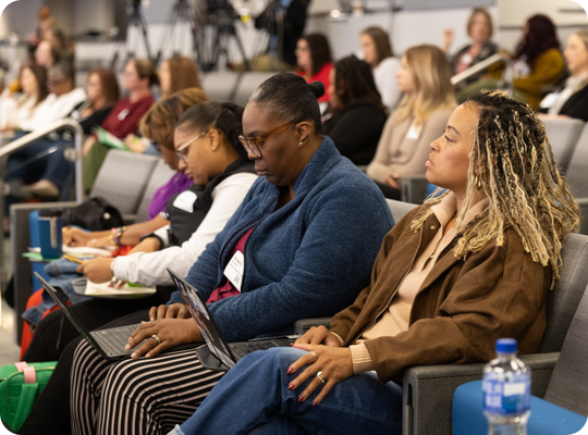 Auditorium full of professionals listening to a presenter.