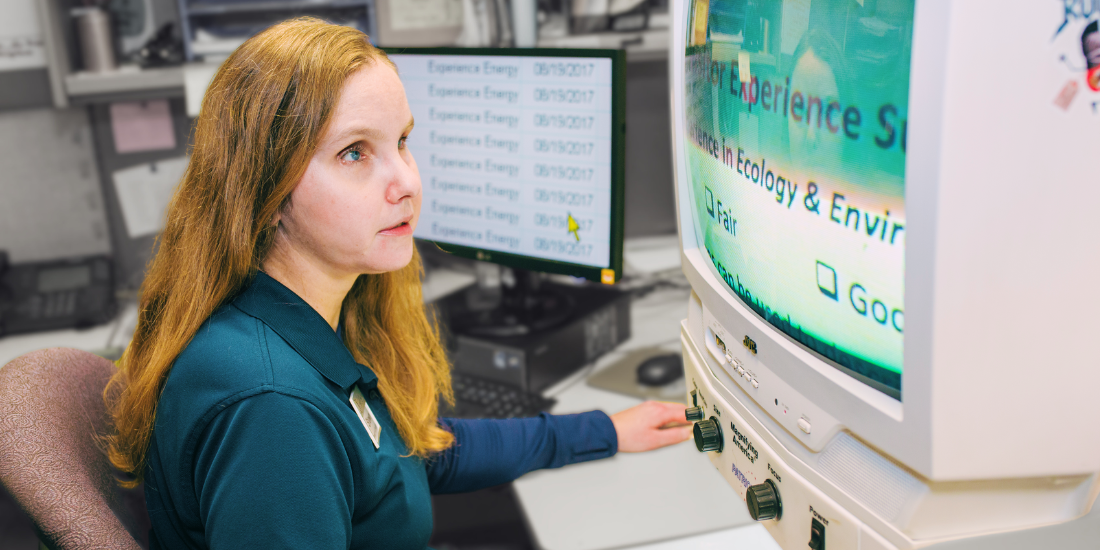 Professional at desk using CCTV to enlarge type on physical document.