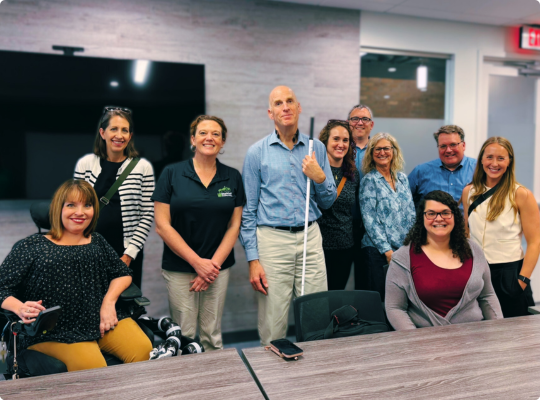 Chris Downey with local architects and SDI staff smile together in a conference room.
